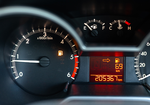 Car dashboard showing fuel level and consumption data used to calculate fuel cost for a trip.