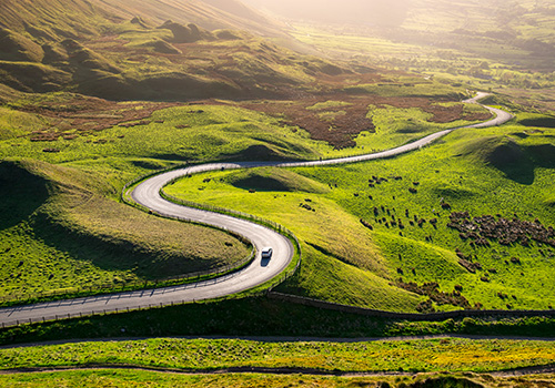 Car driving in the hills on a sunny evening.