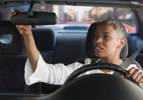Woman adjusting her car mirror.