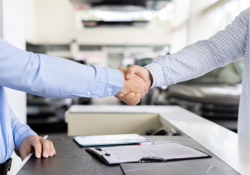 Handshake between a car dealer and a customer at a dealership
