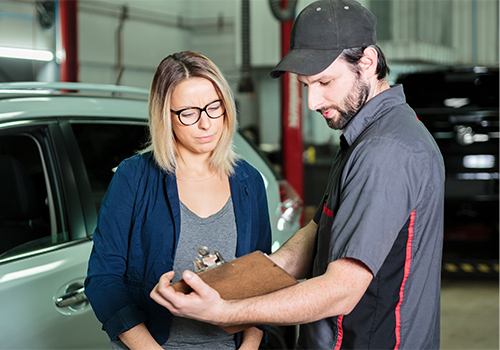 Mechanic explaining car maintenance to a customer in a garage.