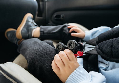 Beb&eacute; sentado no carro, num banco para crianças.
