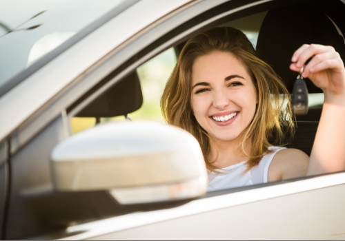 Smiling woman sitting in a car, holding the keys