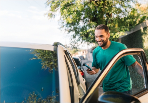 Man getting into a car with his phone in hand