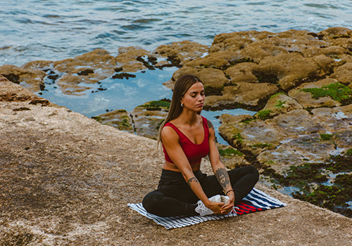 Woman doing yoga by the coast in Portugal