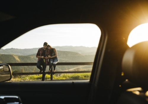 Couple sitting on fence taking selfie on road trip