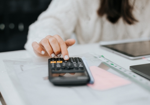 Jovem a fazer contas, usando portátil, tablet e calculadora