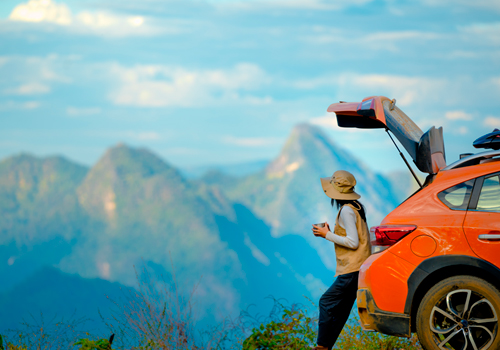 Woman enjoying the view while sitting on the trunk