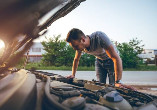 man looking under the raised car bonnet